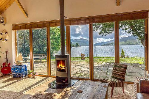 a fireplace in a living room with a view of a lake at The Shore House in Lochgoilhead