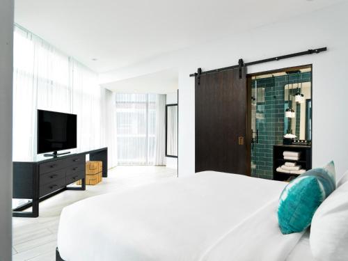a bedroom with a white bed and a television at Wave Resort in Long Branch