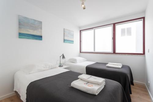 two beds in a white room with windows at FLH Ericeira Cozy House with Terrace in Ericeira