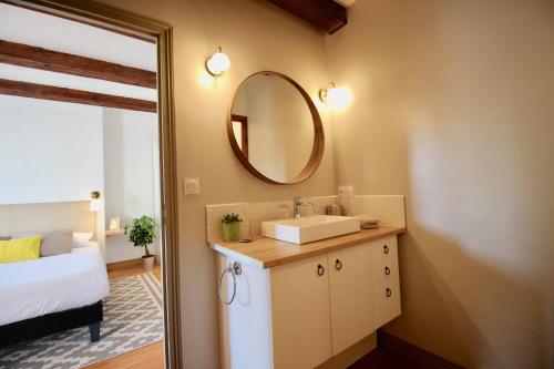 uma casa de banho com um lavatório e um espelho ao lado de uma cama em La Maison Kérès em Kermaria-Sulard