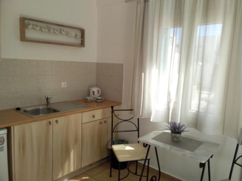una piccola cucina con un lavandino e una finestra di Celeste Apartments a Ornos