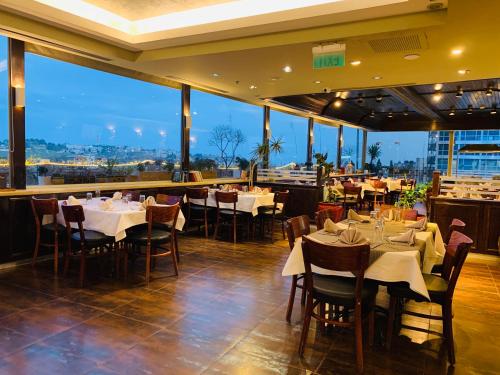 Un restaurante con mesas y sillas y grandes ventanales. en National Hotel - Jerusalem, en Jerusalén