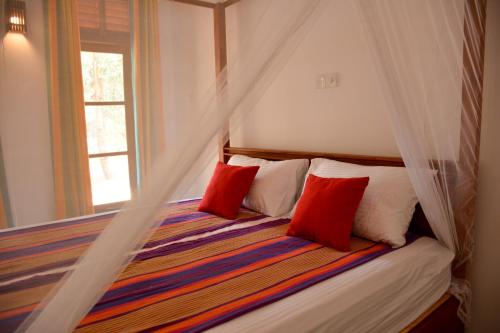 a bedroom with a bed with red pillows and a window at Jackland Holiday Cabanas in Demanhandiya