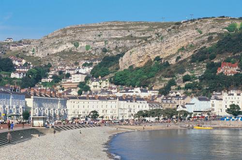 a group of people on a beach in front of a mountain at Imperial Hotel in Llandudno