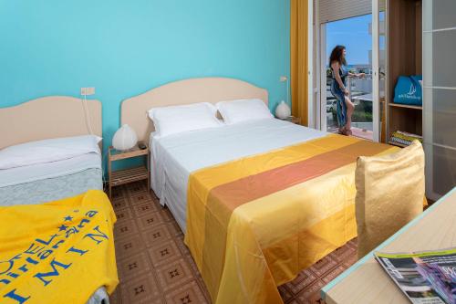 una mujer parada en una habitación con dos camas en G House Rimini Spiaggia, en Rímini