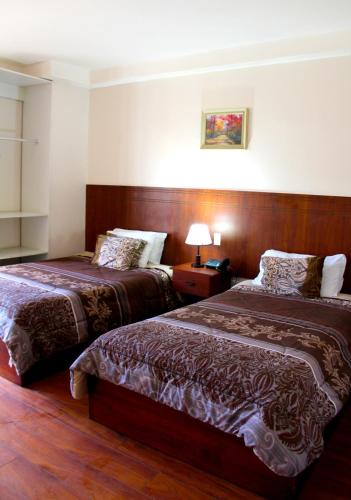 a hotel room with two beds and a lamp at Rio Hotel in Riobamba