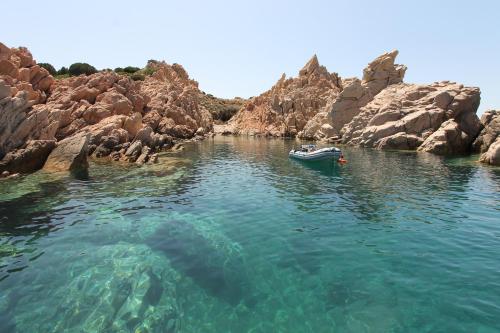 a boat in the water next to some rocks at Costa Paradiso Resort in Costa Paradiso