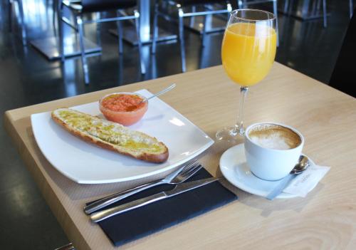 a plate with a hot dog and a glass of orange juice at Hotel La Parada in Getafe
