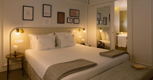 a bedroom with a large white bed and a mirror at Lisboa Pessoa Hotel in Lisbon