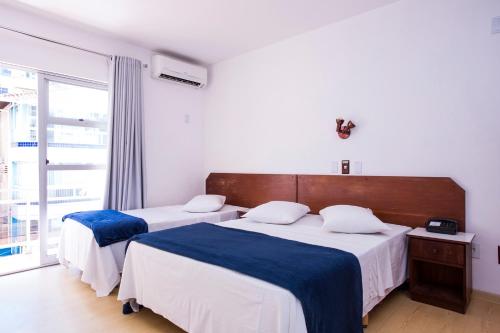 a bedroom with two beds with blue and white sheets at Hotel Itapema Meia Praia in Itapema
