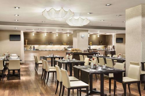 a restaurant with tables and chairs and a kitchen at Ramada Sibiu Hotel in Sibiu