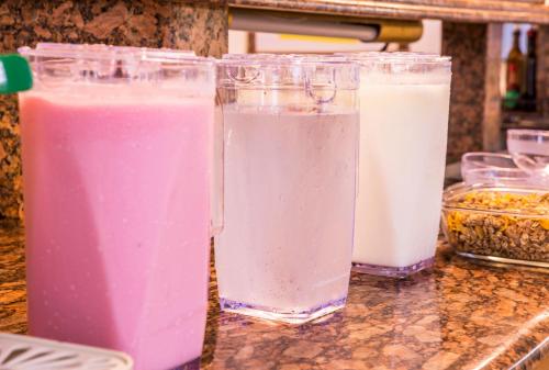 three containers of pink and white milk on a counter at Hotel Itapema Meia Praia in Itapema