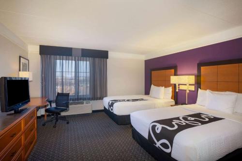 a hotel room with two beds and a flat screen tv at La Quinta by Wyndham St. Louis Westport in Saint Louis