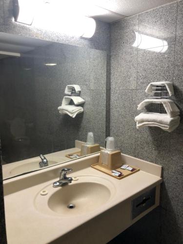 Un baño con lavabo, espejo y toallas. en Capital inn, en Cordele