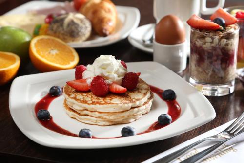 a plate of pancakes with fruit on a table at Best Western Plus Delmere Hotel in London