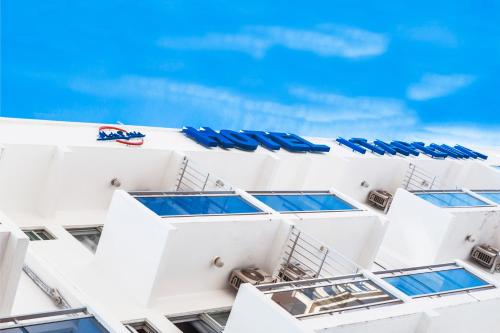 a white building with blue umbrellas and a swimming pool at Hotel Itapema Meia Praia in Itapema