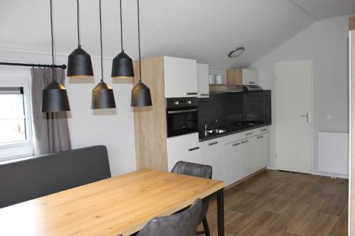 a kitchen with a wooden table and black pendant lights at De Bijsselse Enk, Noors chalet 1 in Nunspeet