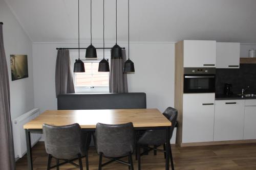 cocina y comedor con mesa de madera y sillas en De Bijsselse Enk, Noors chalet 4, en Nunspeet