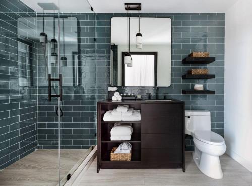baño con lavabo y ducha con azulejos azules en Wave Resort, en Long Branch