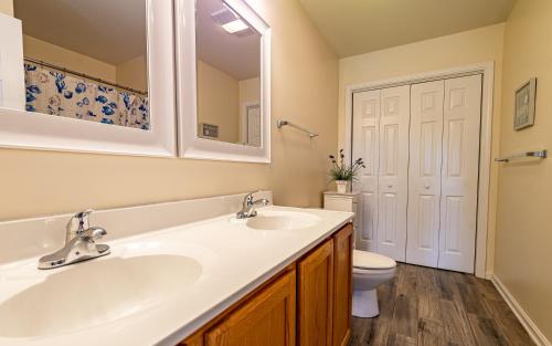 a bathroom with two sinks and a toilet at Follow the Sun in Duck