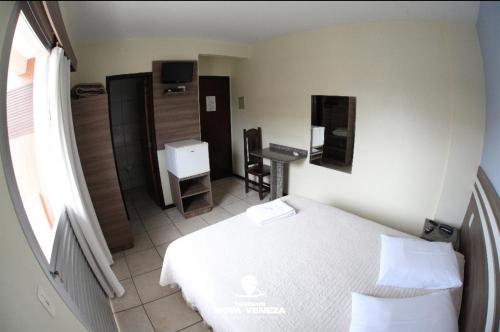 a hotel room with a bed and a bathroom at Hotel Germânia Nova Veneza in Nova Veneza