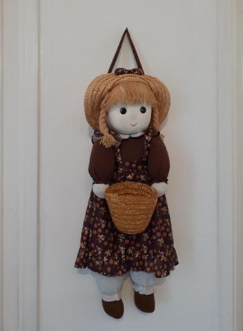 a doll in a dress and hat holding a basket at GrappaLand in Crespano del Grappa
