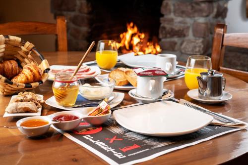 una mesa con desayuno, bebidas y una chimenea en Posada Elbete en Elbete