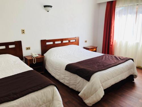 a hotel room with two beds and a phone at Hotel Terrasur in Talcahuano