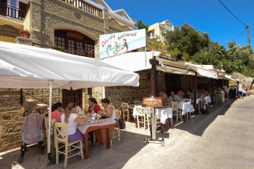 a group of people sitting at tables outside a restaurant at Odyssia in Symi