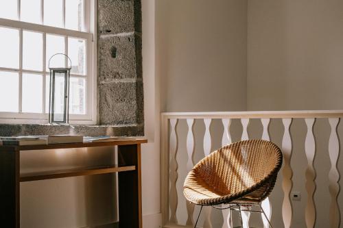 une chaise dans une chambre avec un bureau et une fenêtre dans l'établissement Azores Youth Hostels - Pico, à São Roque do Pico