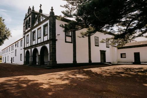 a large white building with a tree in front of it at Azores Youth Hostels - Pico in São Roque do Pico