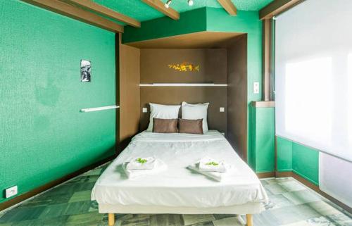 een slaapkamer met een groot bed met een groene muur bij Chipote by Carl-Emilie in Épinal