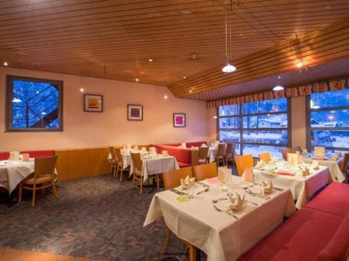 a dining room with white tables and chairs at Hotel Sherlock Holmes & Khana Restaurant "200 m Gondola to Hasliberg ski" in Meiringen