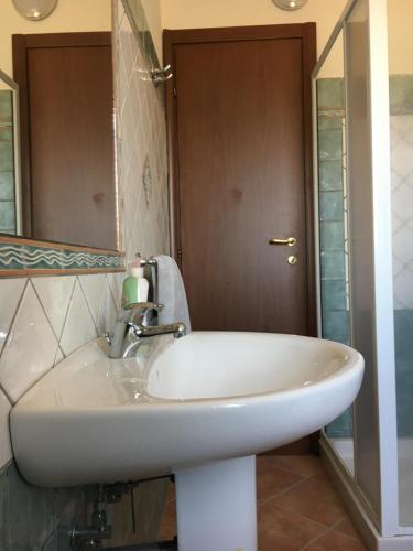 Un lavabo blanco en un baño con espejo. en Domo Sara, en Orosei