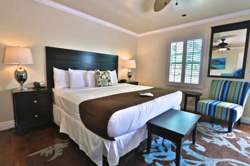 a bedroom with a large bed and a chair at Beach Bungalow Inn and Suites in Morro Bay