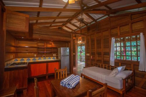 a room with a bed and a kitchen with wooden walls at Casa Viva Lodge in Puerto Viejo