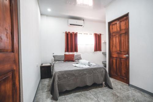 a small bedroom with a bed and a door at Hotel Hoja de Oro Corcovado in Puerto Jiménez