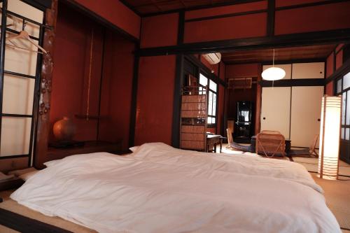 Cama grande en habitación con paredes rojas en 一棟貸ゲストハウス 傾㐂屋 Kabukiya, en Hiroshima