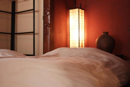 a bedroom with a bed and a vase sitting next to a window at 一棟貸ゲストハウス 傾㐂屋 Kabukiya in Hiroshima