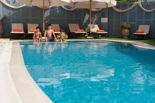 a man and two children sitting in a swimming pool at Anna Platanou Hotel in Parikia