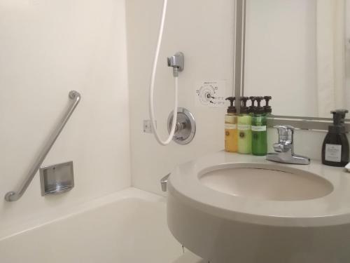 ein weißes Bad mit einem Waschbecken und einer Dusche in der Unterkunft Welco Narita in Narita
