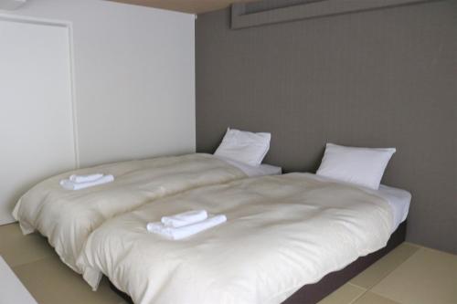 a large white bed with two white towels on it at Stay's OTARU in Otaru