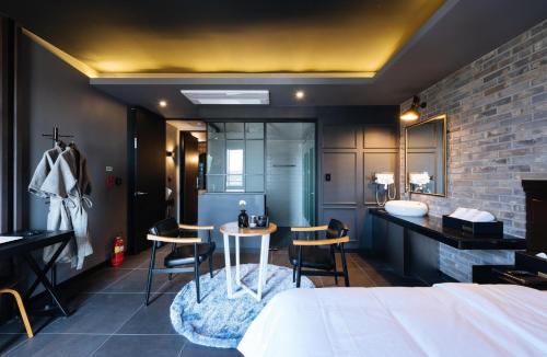 a bedroom with a bed and a table and a bathroom at Boutique Hotel XYM Pyeongtaek in Pyeongtaek