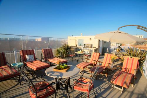a deck with chairs and tables and an umbrella at Venice Suites in Los Angeles