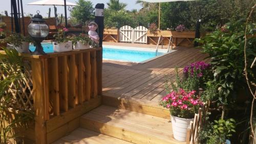 a wooden deck with flowers and a swimming pool at צימר בגליל אביב בבקתה in Galilee