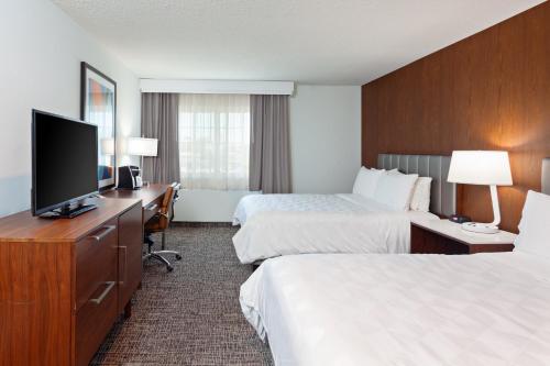 a hotel room with two beds and a flat screen tv at Holiday Inn & Suites San Mateo - SFO by IHG in San Mateo
