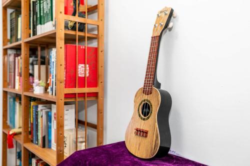 a guitar hanging on a wall next to a book shelf at CSDY House in Shanghai