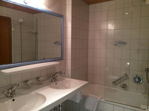 uma casa de banho com um lavatório, uma banheira e um espelho. em Hotel Garni Senn em Sankt Anton am Arlberg