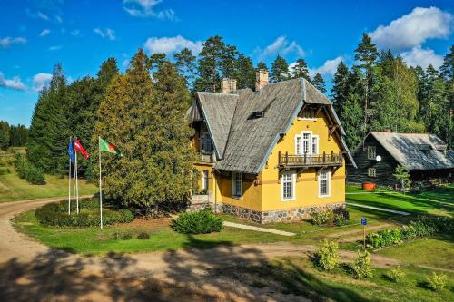 ein gelbes Haus mit grauem Dach und zwei Flaggen in der Unterkunft Bergervilla Boutique Guest House & SPA in Mežmuiža