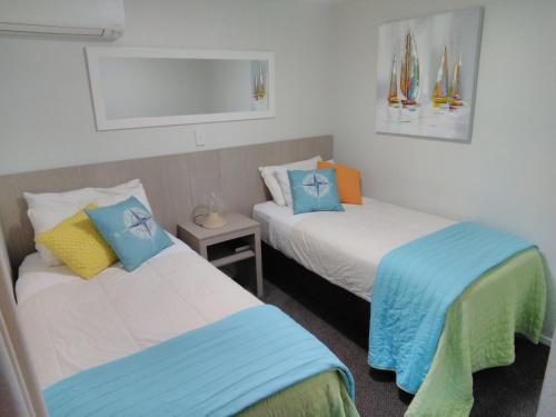 Habitación con 2 camas en azul y blanco en Harbourside Getaway, en One Tree Point